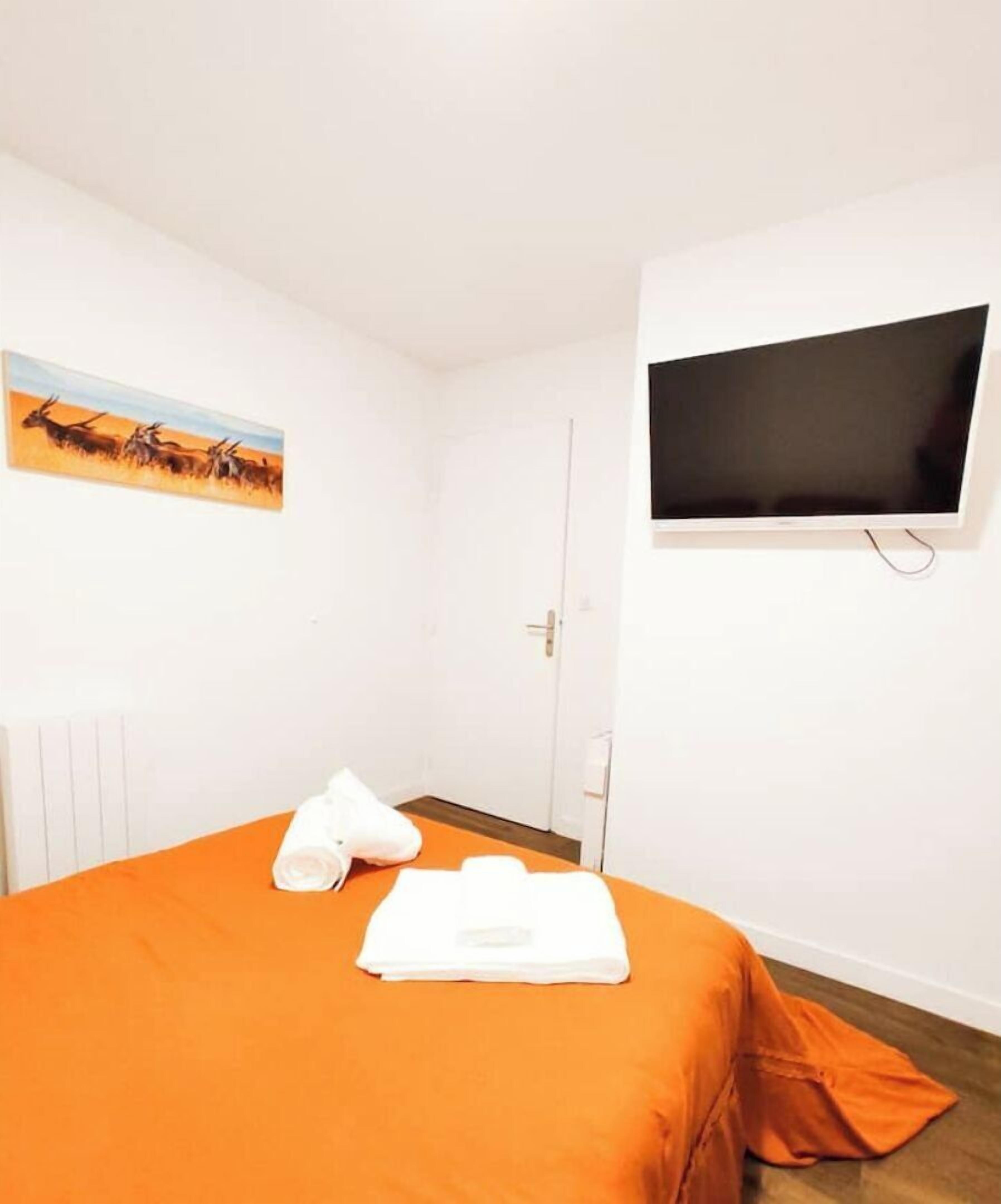 Une chambre d’hôtel avec un lit, une télévision, un tableau et une porte.