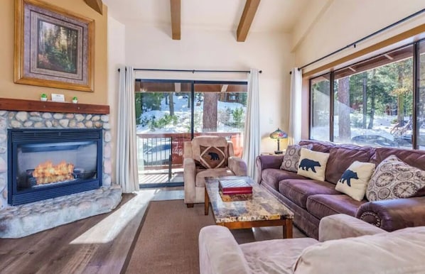 Relax by the fireplace in this inviting living room with a view of the surrounding snowy landscape.