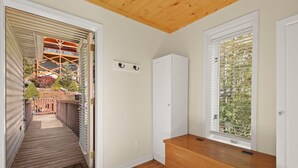 Una habitación con un banco de madera, un armario blanco y una ventana con persianas.