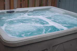 A hot tub with a wooden fence in the background.
