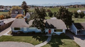A single-story house with a red door, a garage, and a small front yard.