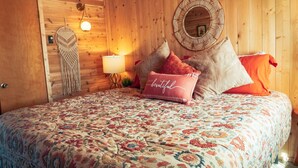 A wooden-paneled room with a bed, a wall-mounted lamp, and a decorative mirror.