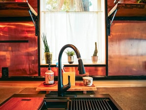 Un área de cocina con un grifo moderno, una encimera de madera y diversos utensilios de cocina.