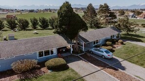 Ein zweistöckiges Haus mit Garage, Auffahrt und einem geparkten Auto davor.
