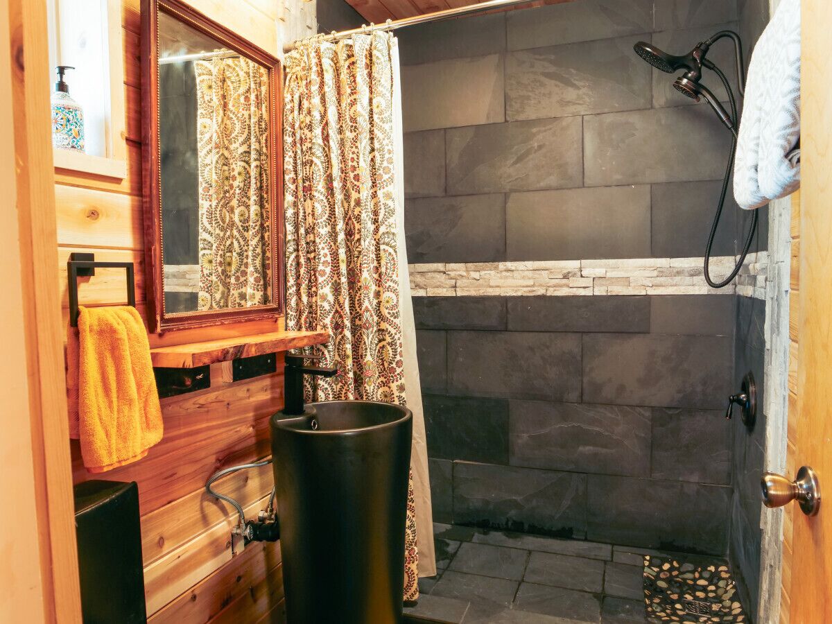 Un baño con ducha, tocador de madera, espejo y perchero para toallas.