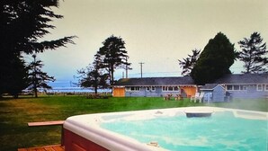A hot tub on a wooden deck with a view of a house and trees in the background. - Rm 4 Sequim lavender · 4-Water View-Beach access-Sequim's Lavender Room (Sequim)