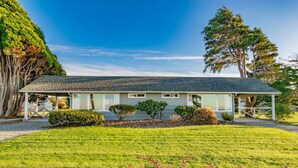 A single-story house with a gabled roof, surrounded by a well-maintained lawn and various shrubs. - Rm 4 Sequim lavender · 4-Water View-Beach access-Sequim's Lavender Room (Sequim)