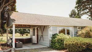 Un petit bâtiment d’un seul étage, doté d’un patio couvert, d’un jacuzzi et d’une grande fenêtre.