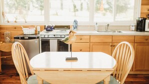 Une cuisine avec des meubles de rangement en bois, une cuisinière, un évier et une table à manger avec des chaises.