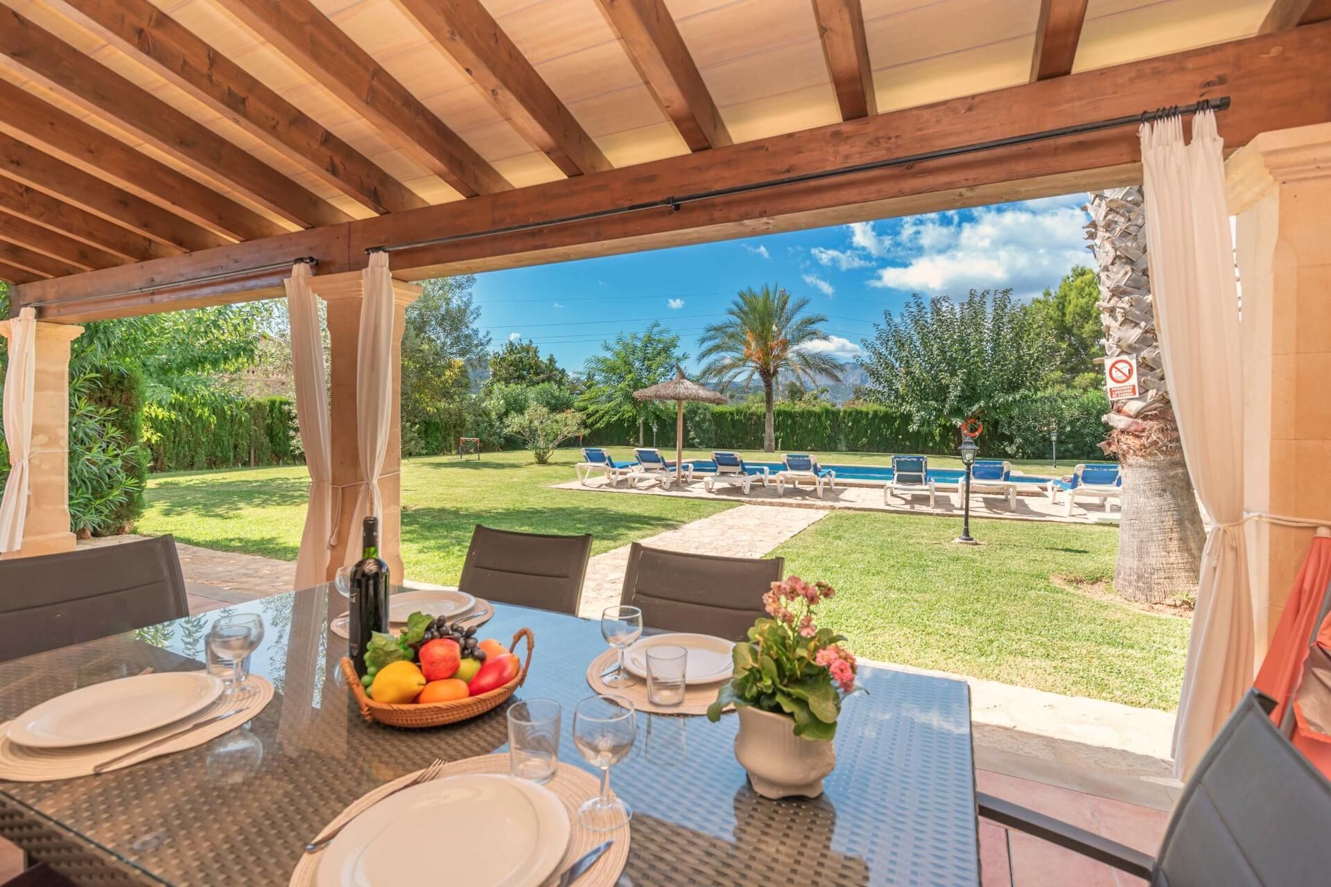 An outdoor dining area with a view of a pool and garden.