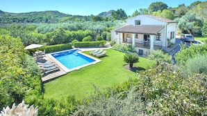 Una casa con piscina, rodeada de exuberante vegetación y colinas.