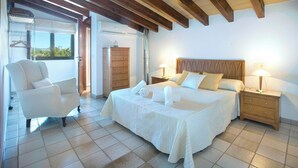 Un dormitorio con una cama grande, dos mesitas de noche con lámparas, un armario de madera, una silla y una ventana con vistas.