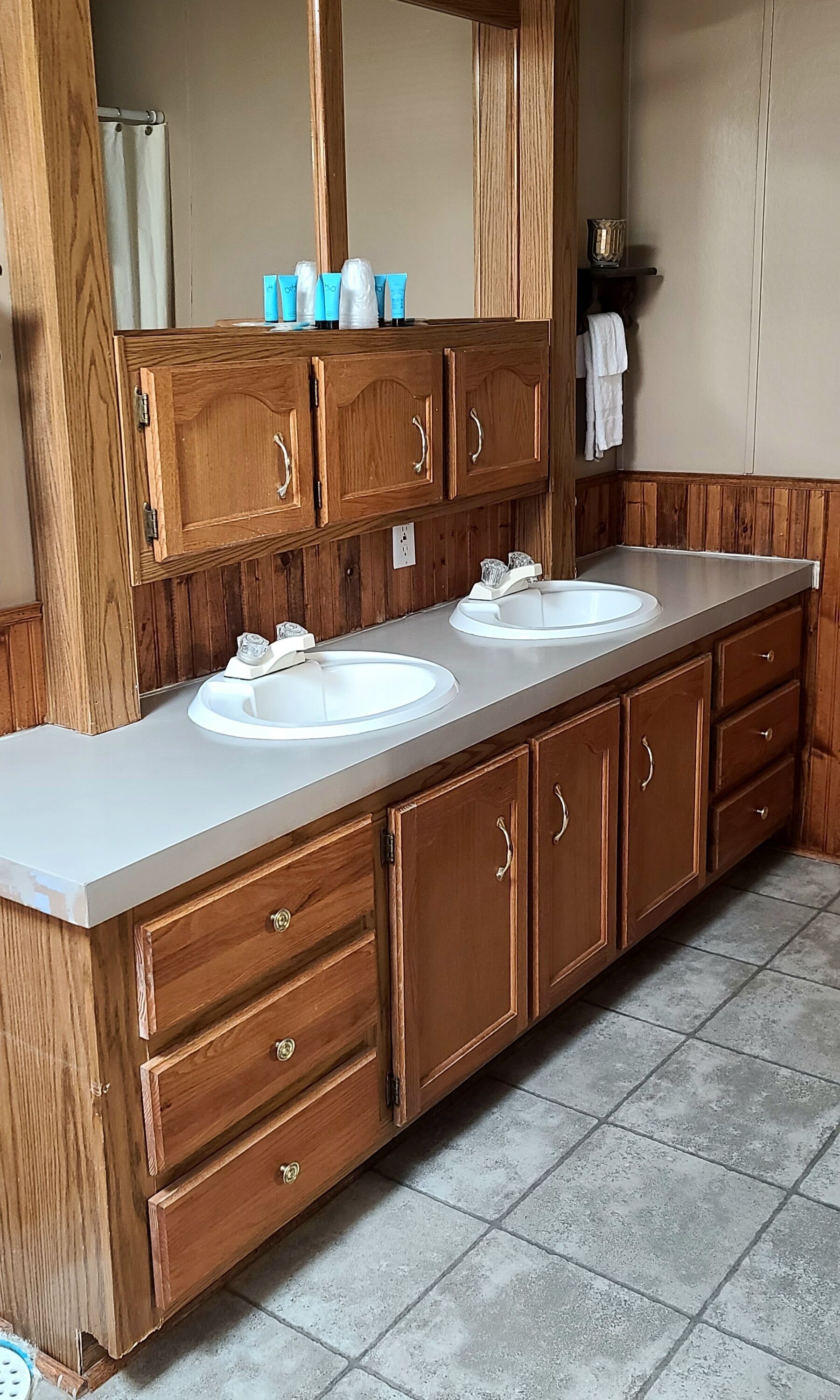 Un baño con muebles de madera, dos lavamanos y un espejo sobre ellos.