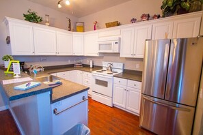 A kitchen with white cabinets, a stainless steel refrigerator, a microwave, and a stove. - Heart of Downtown 2-Bedroom Apt, Mountain Views, Full Kitchen, Walk to Eats (Glenwood Springs)