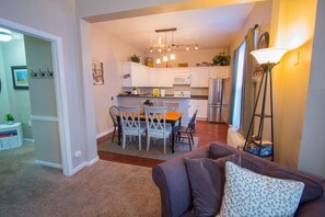 A modern kitchen with white cabinets, a dining area with a table and chairs, and a floor lamp. - Heart of Downtown 2-Bedroom Apt, Mountain Views, Full Kitchen, Walk to Eats (Glenwood Springs)