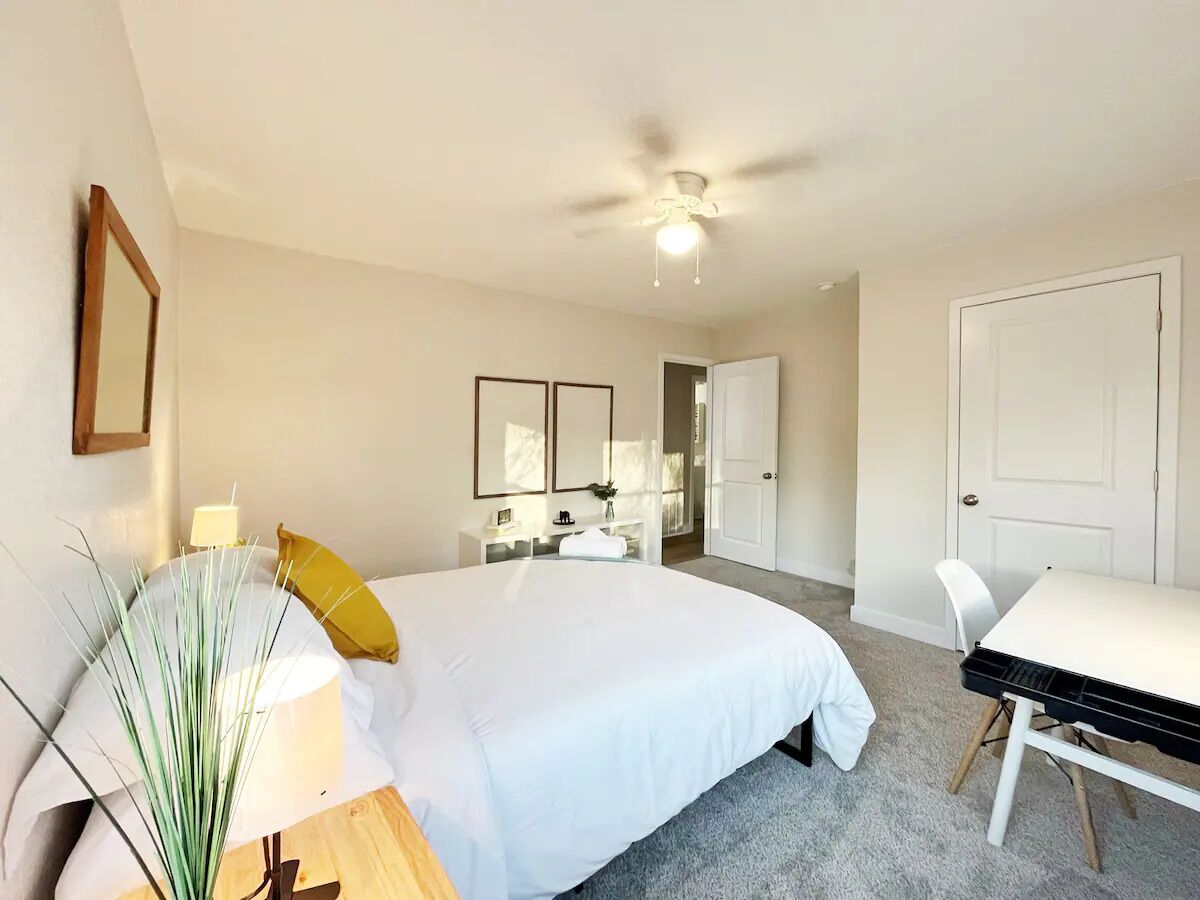 Une chambre à coucher comprenant un lit, une table de chevet, une lampe et un bureau avec une chaise.