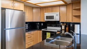 Una cocina moderna con electrodomésticos de acero inoxidable, armarios de madera y encimera negra.