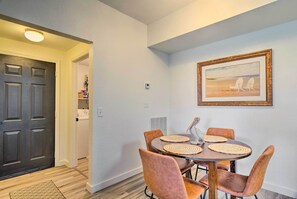 A dining area with a round table, four chairs, and a wooden chair with a pelican design. - Work, Swim + Play in Ft Myers: Resort Condo Stay! (Fort Myers)