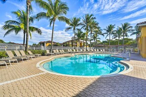 A pool area with lounge chairs and palm trees. - Work, Swim + Play in Ft Myers: Resort Condo Stay! (Fort Myers)