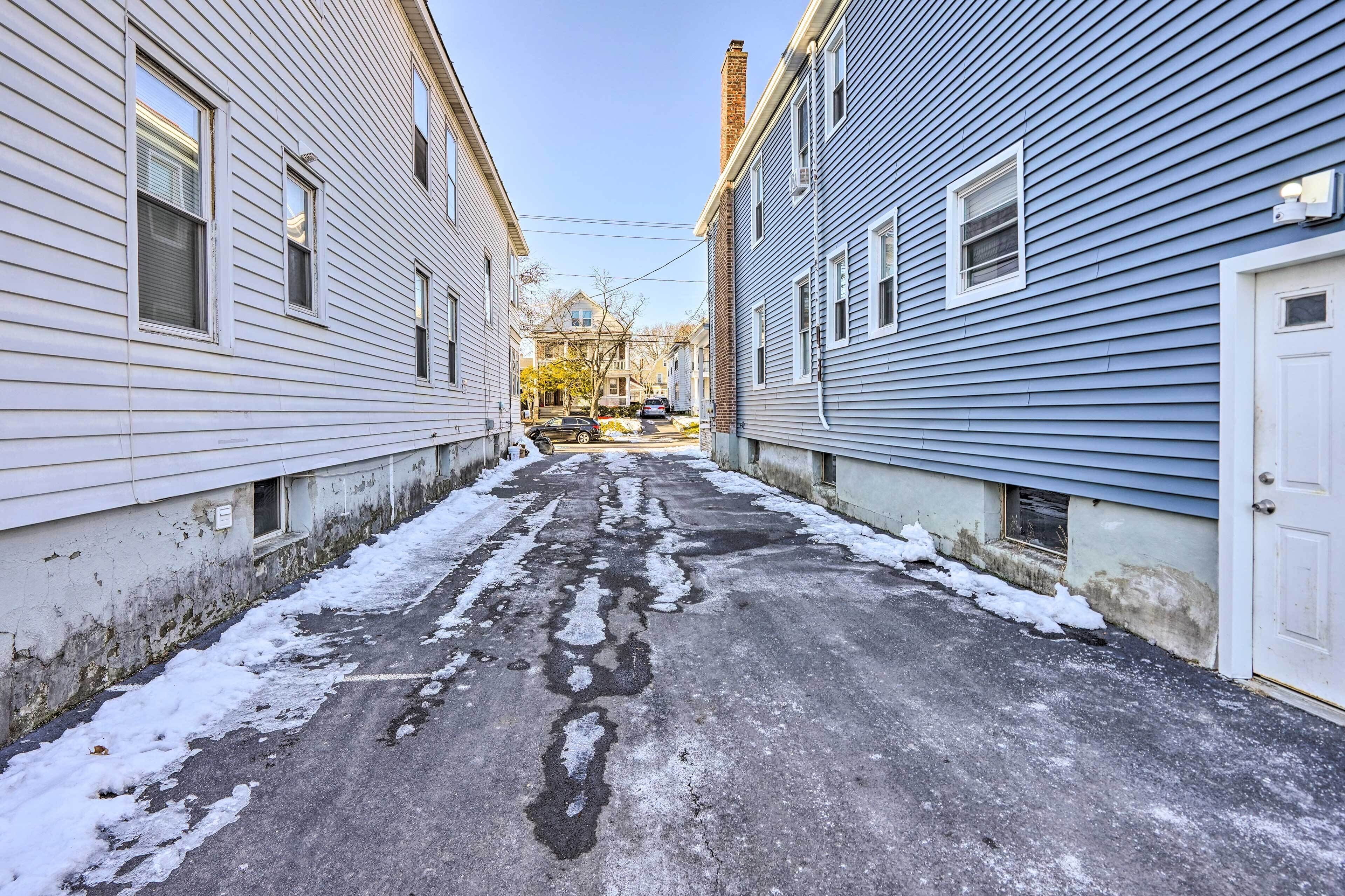 A narrow street flanked by two-story houses with visible wear and patches of snow.