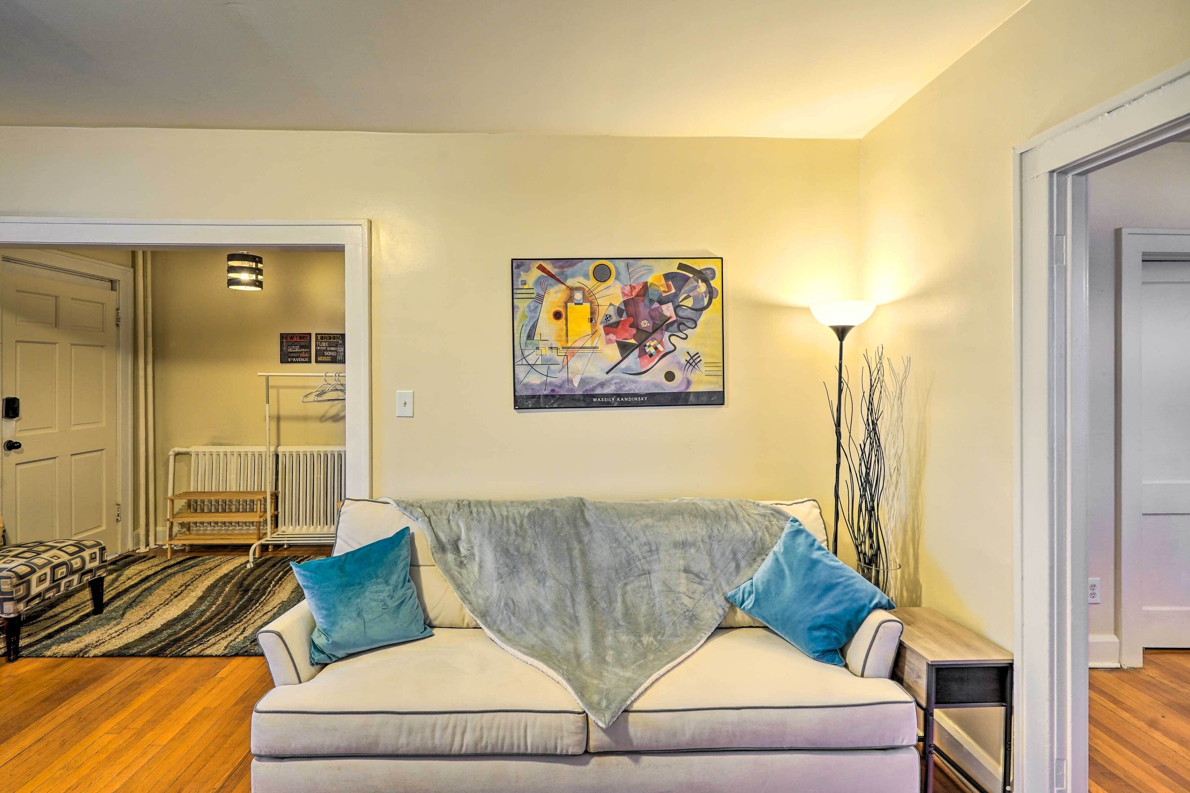 A living room with a sofa, a painting, and a lamp.