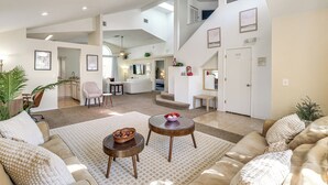 A spacious living area with a high ceiling, a staircase, and a kitchen in the background. - 5 Mi to Disney! Family Getaway w/ Poolside Oasis (Kissimmee)