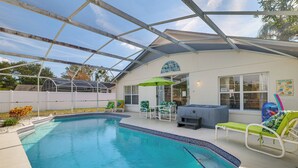 A swimming pool with a glass enclosure, lounge chairs, and a barbecue area. - 5 Mi to Disney! Family Getaway w/ Poolside Oasis (Kissimmee)