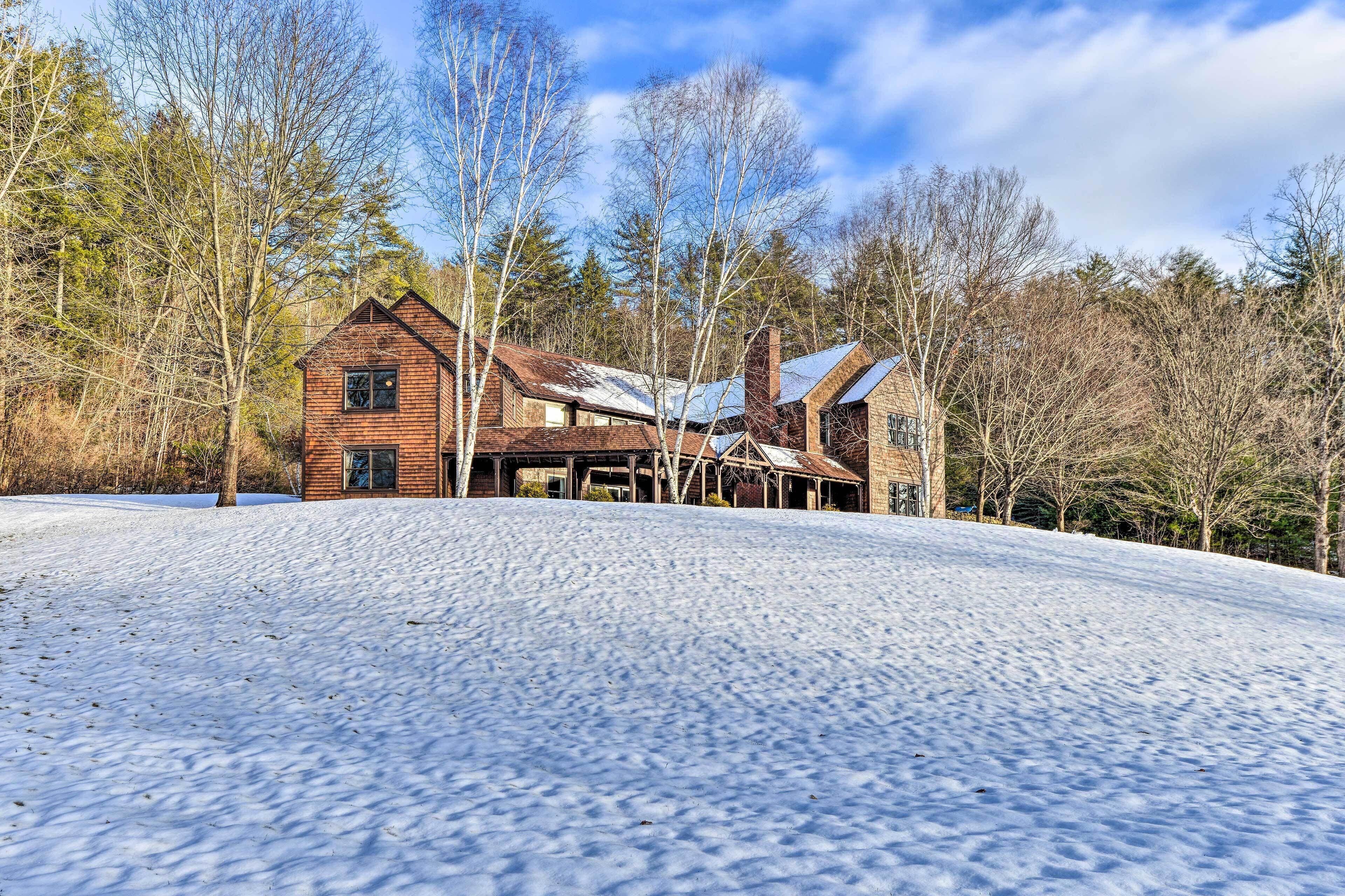 A rustic cabin with a wooden exterior, surrounded by snow-covered ground and trees.