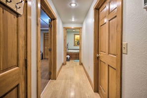 A narrow hallway with wooden doors on both sides, leading to a bathroom with a sink and mirror.