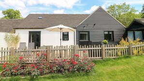 En række moderne, toetagers huse med et træhegn og en have med røde blomster.
