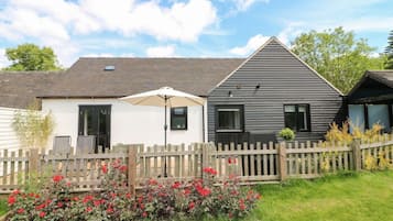 Une rangée de maisons de campagne modernes à deux étages, avec une clôture en bois et un jardin agrémenté de fleurs rouges.