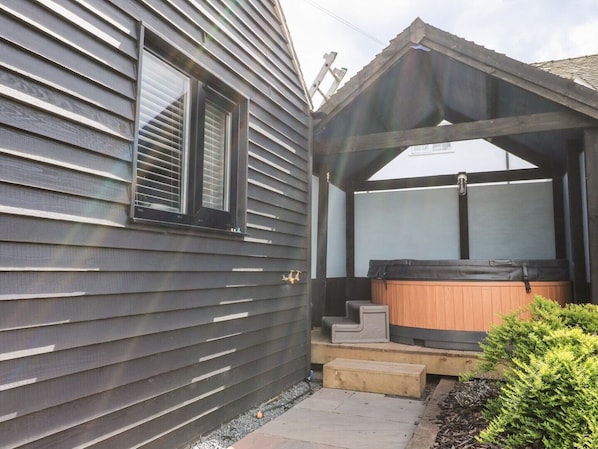 A house with a covered porch, a hot tub, and a small staircase leading to the porch.