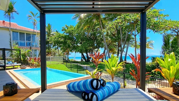 A poolside lounge area with a covered seating area, a pool, and tropical plants. - Seadreams Mission Beach (Mission Beach)