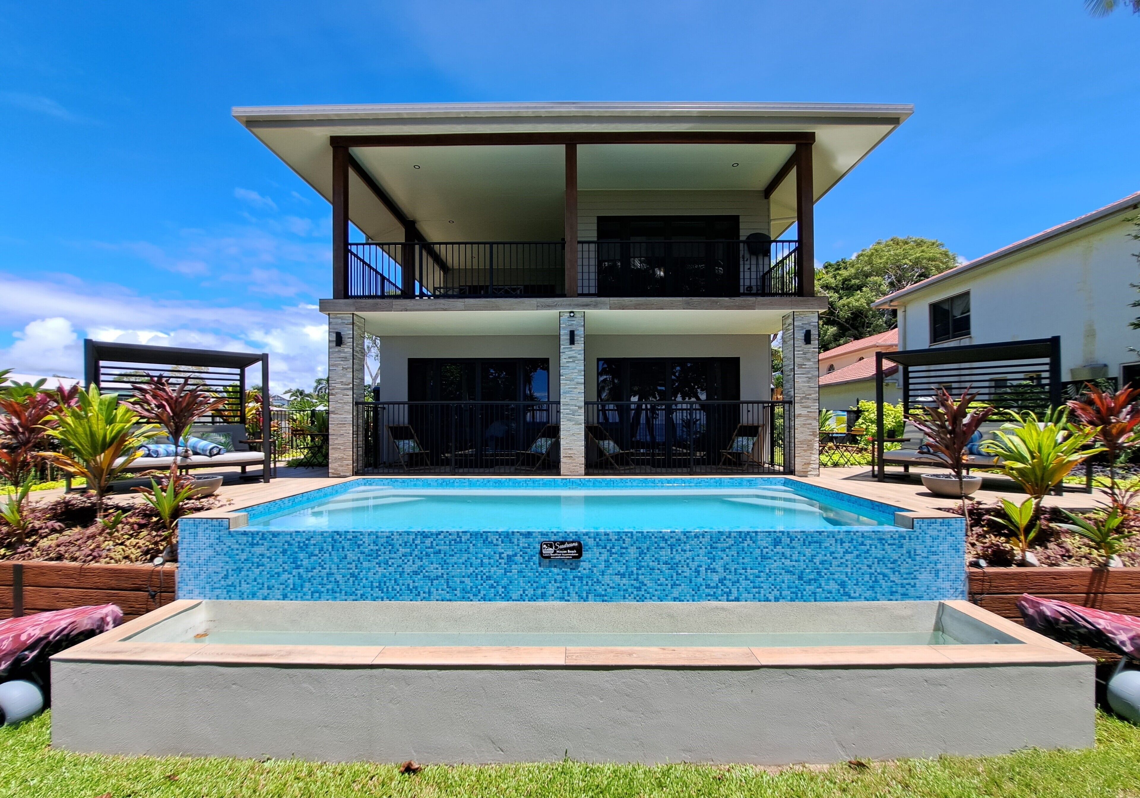 A two-story house with a swimming pool in front.