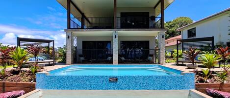 A two-story house with a swimming pool in front.
