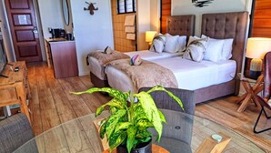 A hotel room with a bed, bedside tables, a desk, and a potted plant. - Seadreams Mission Beach (Mission Beach)