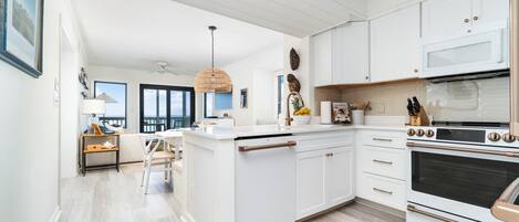 A modern kitchen with white cabinetry, a central island, and a large oven.