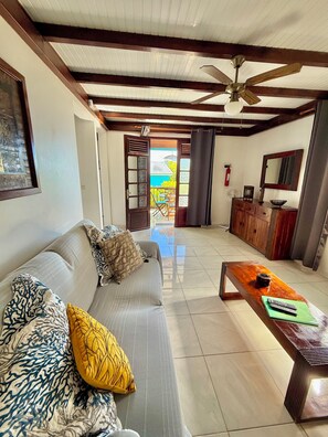 A living room with a sofa, coffee table, and a view to an outdoor area. - LES VILLAS PAMEYAQUE/ LA VILLA PAME with a pool and a view of the Caribbean Sea (Rivière-Salée)