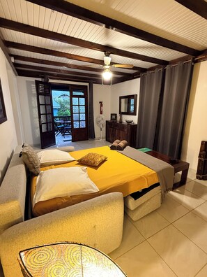 A room with a bed, a sofa, a fan, a mirror, and a view of the outdoors. - LES VILLAS PAMEYAQUE/ LA VILLA PAME with a pool and a view of the Caribbean Sea (Rivière-Salée)