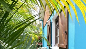 A blue building with wooden shutters, surrounded by lush green foliage. - LES VILLAS PAMEYAQUE/ LA VILLA PAME with swimming pool, facing the Caribbean Sea (Rivière-Salée)