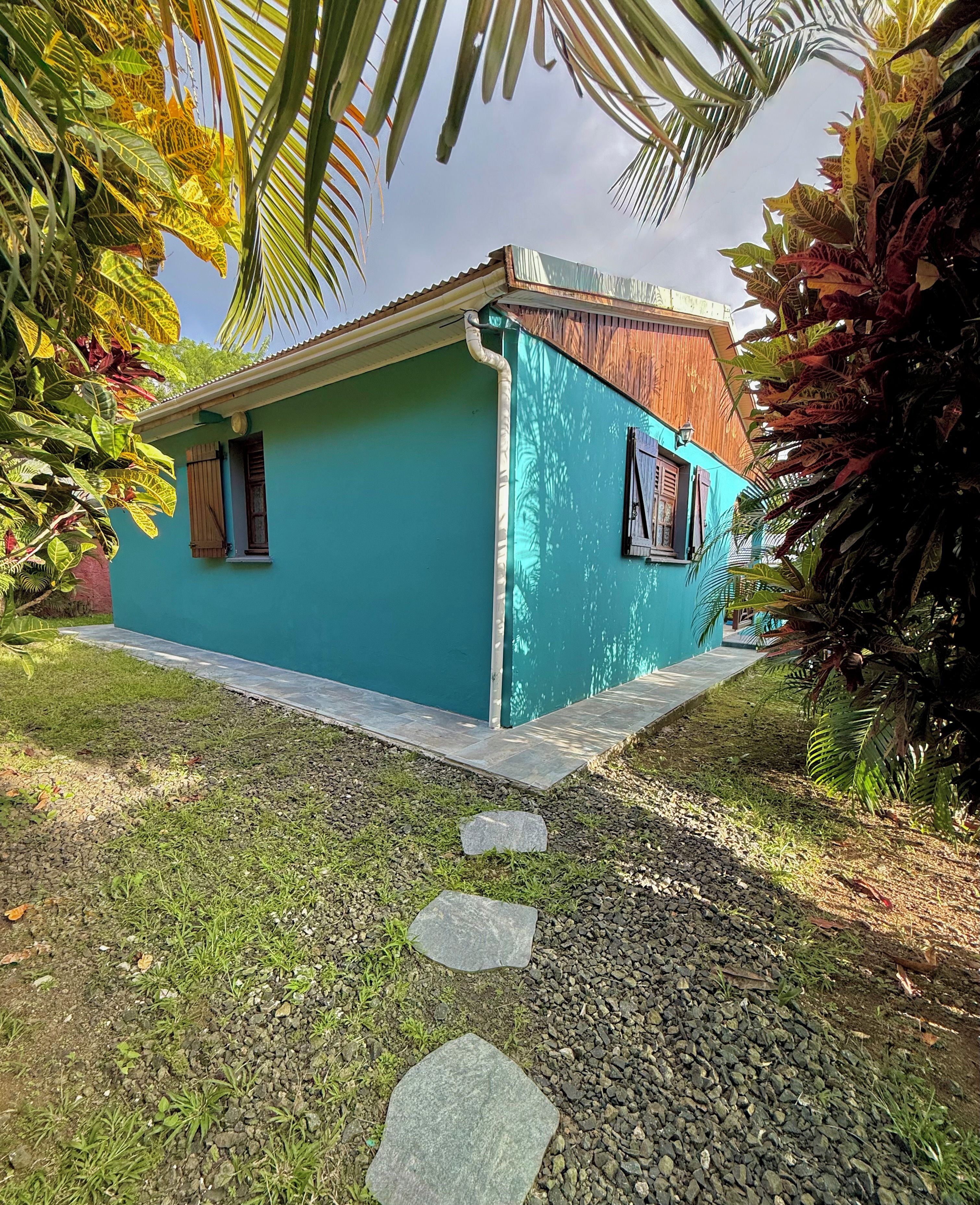 Une maison avec un toit en pente et un mur latéral plat, peint d’une couleur unie.