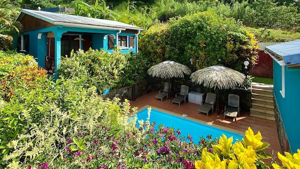 A blue house with a pool, surrounded by lush greenery and colorful flowers. - LES VILLAS PAMEYAQUE/ LA VILLA PAME with swimming pool, facing the Caribbean Sea (Rivière-Salée)