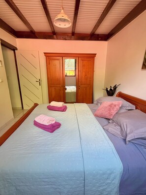 Camera da letto con due letti, un armadio in legno e una ventola a soffitto.