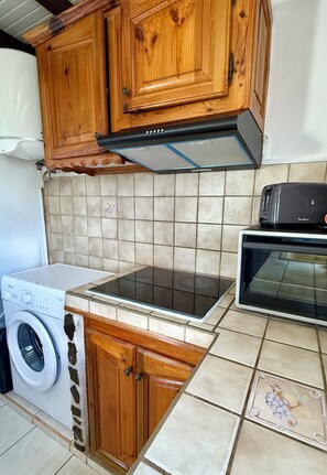 Una cucina con mobili in legno, forno integrato, lavatrice e pannelli di piastrelle a parete.