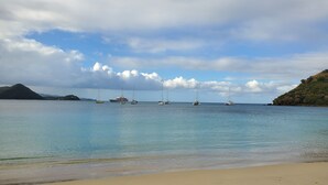 A beach with clear water, a sandy shore, and several sailboats anchored in the distance. - Panoramic Views as Sunsets await, Close to Beaches, Sandals Golf and Cabot Golf (Cap Estates)