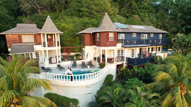 A resort with a pool, multiple buildings, and lush greenery. - Panoramic Views as Sunsets await, Close to Beaches, Sandals Golf and Cabot Golf (Cap Estates)
