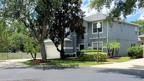 A two-story residential building with a garage, surrounded by well-maintained lawns and trees.