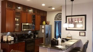 A modern kitchen with wooden cabinets, stainless steel appliances, and a bar area.
