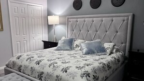 A bedroom with a tufted headboard, floral bedding, and a matching bench.