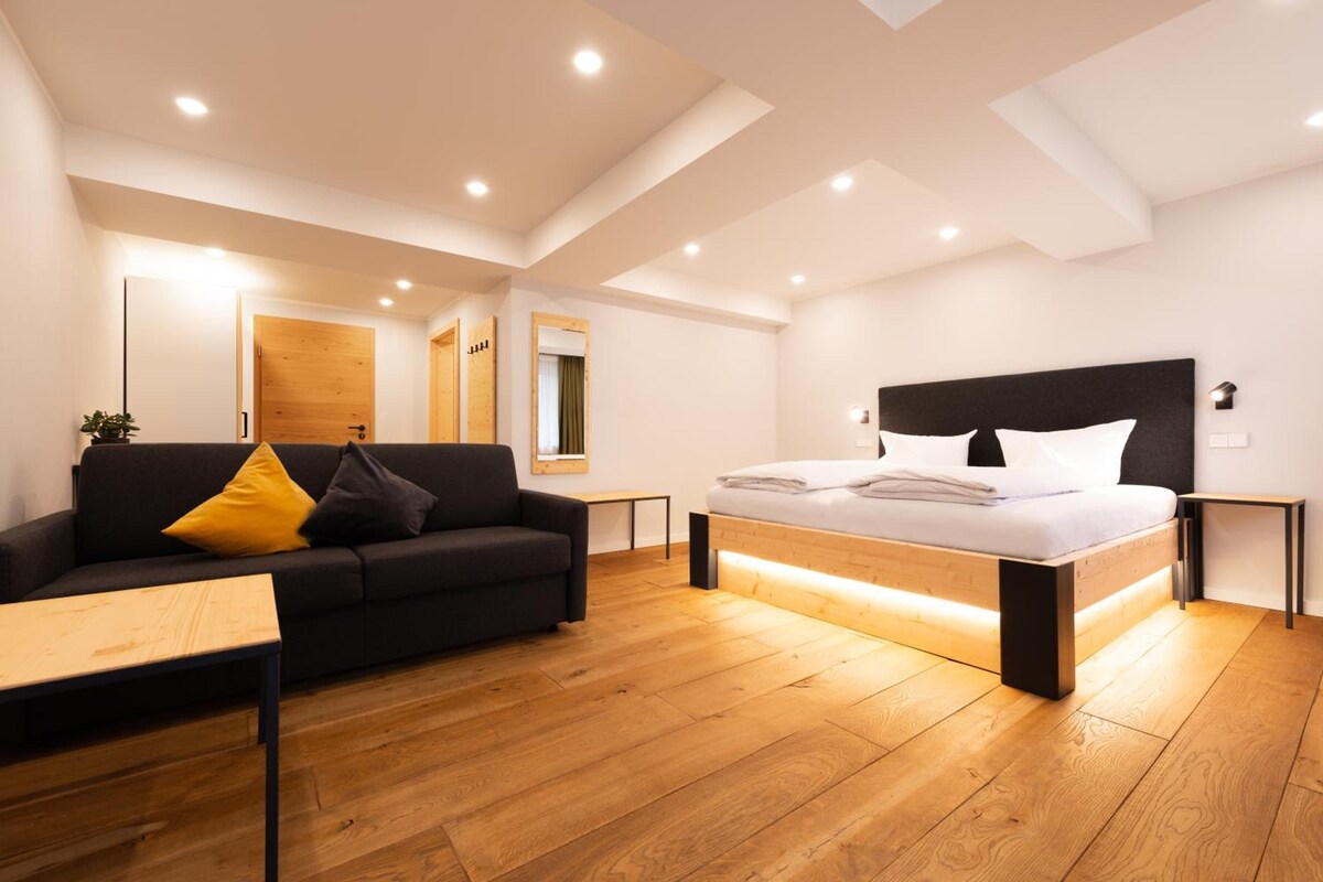 Un dormitorio moderno con cama, sofá y piso de madera.